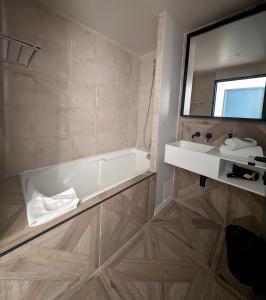 a bathroom with a bath tub and a mirror at OVYO Hôtel in Toulouse