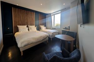 1 dormitorio con 2 camas, mesa y silla en OVYO Hôtel en Toulouse