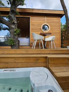 a deck with a tub and a bed and a table at Caban'AO in Saint-Just-et-Vacquières