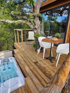 a deck with a hot tub and a table at Caban'AO in Saint-Just-et-Vacquières +3 photos