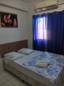een bed met blauwe gordijnen en twee handdoeken erop bij HOTEL DIVINO PAI ETERNO 2 in Aparecida