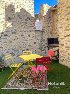 una mesa amarilla y 4 sillas frente a un edificio de piedra en Wellness Retreat - Unique Village House in Bouleternère, en Bouleternère