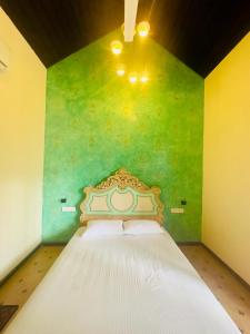 een slaapkamer met een bed met een groene muur bij The Kabok Villa by Vivanya in Ambalangoda