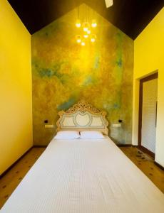 a bedroom with a white bed with a yellow wall at The Kabok Villa by Vivanya in Ambalangoda