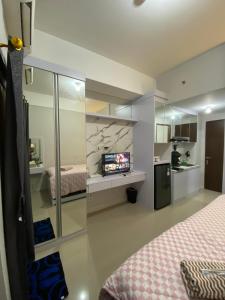 RawabugelにあるAPARTEMENT TRANSPAK JUANDA By Enjoy Roomのベッド2台と壁掛けテレビが備わる客室です。