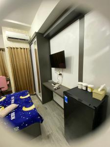 RawabugelにあるAPARTEMENT TRANSPAK JUANDA By Enjoy Roomのベッドルーム1室(ベッド1台、デスク、テレビ付)