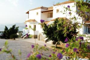 a white house with purple flowers in front of it at Studios Maniati in Elafonisos