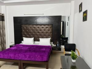 - une chambre avec un lit violet et une chaise dans l'établissement Staykr Rooms & BnB, à Gurgaon