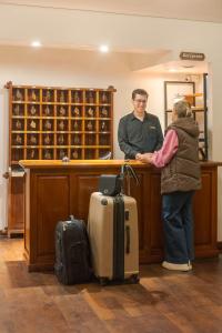 a man and a woman standing at a counter with luggage at Le Chatelet in San Martín de los Andes