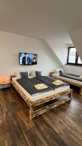 a bedroom with two beds and a tv on the wall at Apartmán KUGA in Mikulov