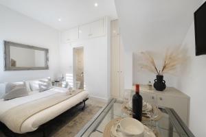 a white bedroom with a bed and a glass table at Livestay Tranquil Studio Retreat in Harrow in Harrow