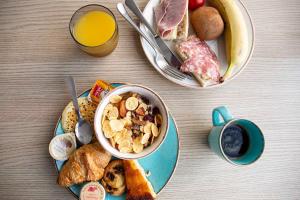 a table with a bowl of cereal and a plate of food at Hotel Port Marine in Sète