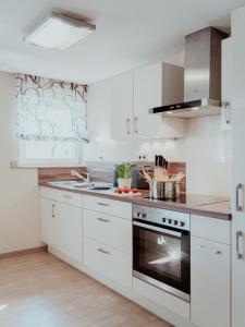 een keuken met witte kasten en een fornuis met oven bij Ferienwohnung Morgensonne in Appenweier