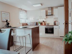 a kitchen with white cabinets and a counter with stools at Ferienwohnung Morgensonne in Appenweier