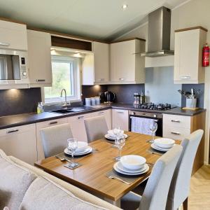 a kitchen with a wooden table with chairs around it at Caplor Glamping & Lodges in Hereford