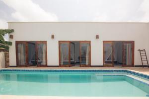 einen Pool vor einem Haus mit Glastüren in der Unterkunft Bukoba Villas - Iris - Private Pool, AC & Wi-Fi in Nungwi