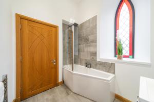 a bathroom with a bath tub and a wooden door at The Church Front in Montrose