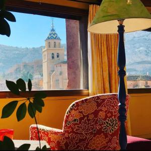 a lamp sitting next to a chair in front of a window at Casa de Santiago in Albarracín