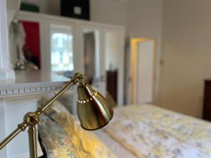 a gold lamp sitting next to a bed at 15 min to The Heart of London - Charming 2 bed Apartment in London