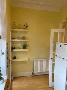 a kitchen with yellow walls and shelves and a refrigerator at 10 min to The Heart of London - Zone 2 - Charming 2 bed Apartment in London