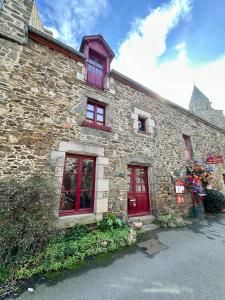 ein altes Steingebäude mit roten Türen und Fenstern in der Unterkunft L'abri-côtier in Saint-Suliac