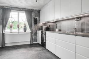 cocina con armarios blancos, fregadero y ventana en Guestly Homes - 4BR Cozy House near windfarm, en Piteå