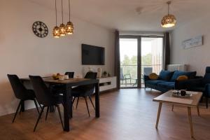 a living room with a table and a blue couch at Apartament Premium PINEA 523 in Pobierowo