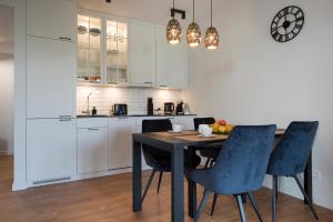 a kitchen with a table and blue chairs in a kitchen at Apartament Premium PINEA 523 in Pobierowo