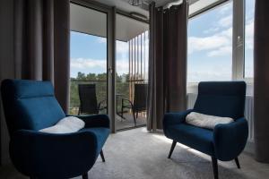 two blue chairs in a living room with large windows at Apartament Premium PINEA 523 in Pobierowo