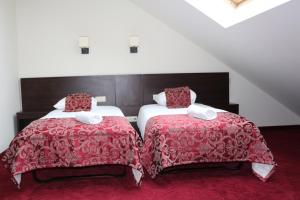 two beds in a room with red blankets and pillows at Rezidencija Grįžulo ratai in Sasnava +54 photos