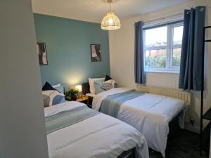 two beds in a room with a window at Charming Home in Stourport Sleeps10 with Wifi&Parking by PureStay Short Lets in Stourport