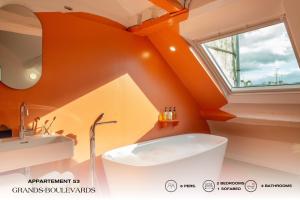 an orange bathroom with a tub and a sink at Beauquartier - Grands Boulevards in Paris