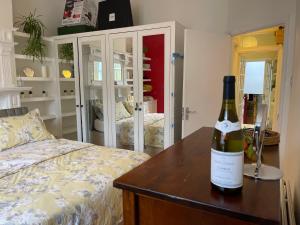 eine Flasche Wein auf einem Tisch neben einem Bett in der Unterkunft 15 min to The Heart of London - Charming 2 bed Apartment in London