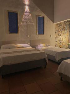 a bedroom with two beds and two windows at EcoHotel Inka Minka in Santa Marta