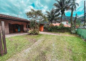 ein Backsteinhaus mit einem Hof mit Palmen in der Unterkunft Casa com 3 quartos a 400 metros da Praia in Ubatuba