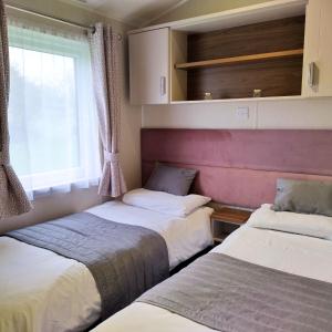 two beds in a small room with a window at Caplor Glamping & Lodges in Hereford