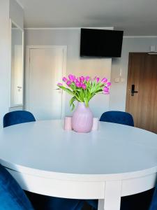 a white table with a vase of flowers on it at Baltic Gdansk OLD TOWN in Gdańsk