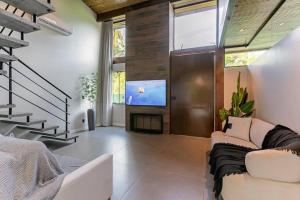 uma sala de estar com um sofá e uma televisão de ecrã plano em Recanto Natureza em Florianópolis