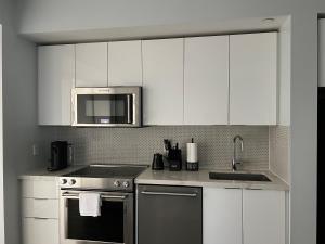 a kitchen with white cabinets and a stove and a microwave at Waterfront Luxury Condo in Toronto