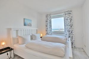 a white bedroom with two beds and a window at Strandschlößchen Strandschlösschen Appartement 5 in Haffkrug