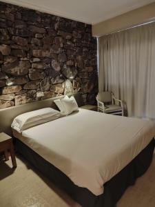 a bedroom with a large bed and a stone wall at Hostal Mar del Plata in El Arenal