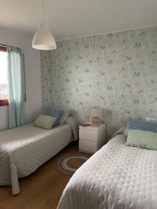 a bedroom with two beds and a wall with flowers at O Recuncho de Belén in Baiona