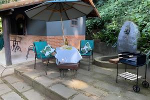 a table and chairs with an umbrella on a patio at Cabana no meio do Vale! (Itaipava-Araras) in Petrópolis