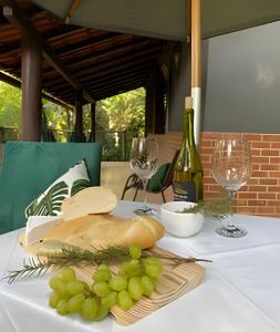 een tafel met een bos druiven en een fles wijn bij KORU Cabana - Paz & Romance in Petrópolis