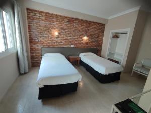 a room with two beds and a brick wall at Hostal Mar del Plata in El Arenal