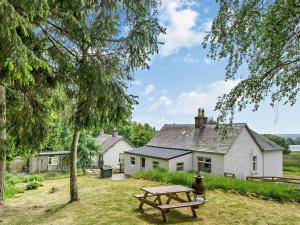 een picknicktafel voor een wit huis bij Upper Hillside Cottage in Bridge of Cally