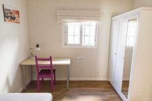 um quarto com uma mesa, uma cadeira e uma janela em BBTK Eco-Hostel em Málaga