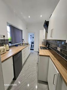 a kitchen with white cabinets and wooden counter tops at By the Joyous Stays in Stoke on Trent