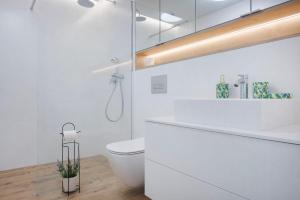 a white bathroom with a toilet and a sink at Apartament Premium Sea View PINEA 704 in Pobierowo