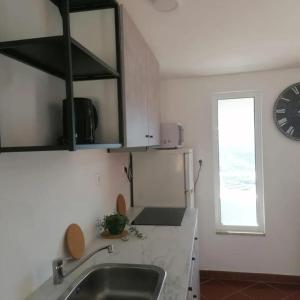 uma cozinha com um lavatório e um relógio na parede em Casa Barqueiro em Folgosa
